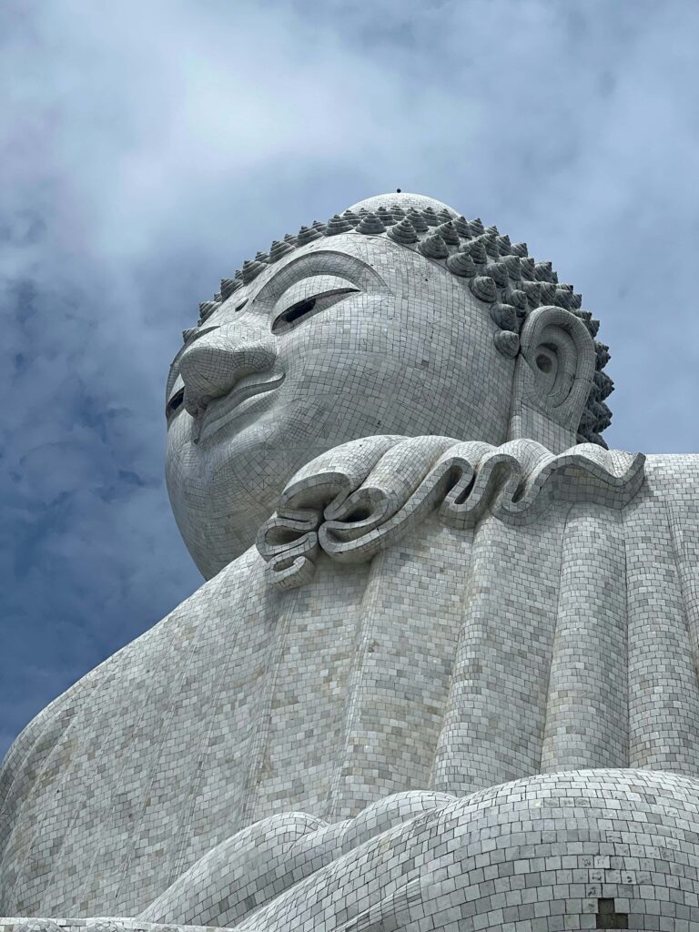 Close-up of the majestic Big Buddha statue in Phuket, Thailand, against a cloudy sky.