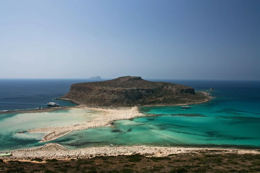 Honeymoon destinations all inclusive Greece: A close-up view of a rugged rock formation against the backdrop of the turquoise waters of the Aegean Sea, offering a serene and romantic setting.