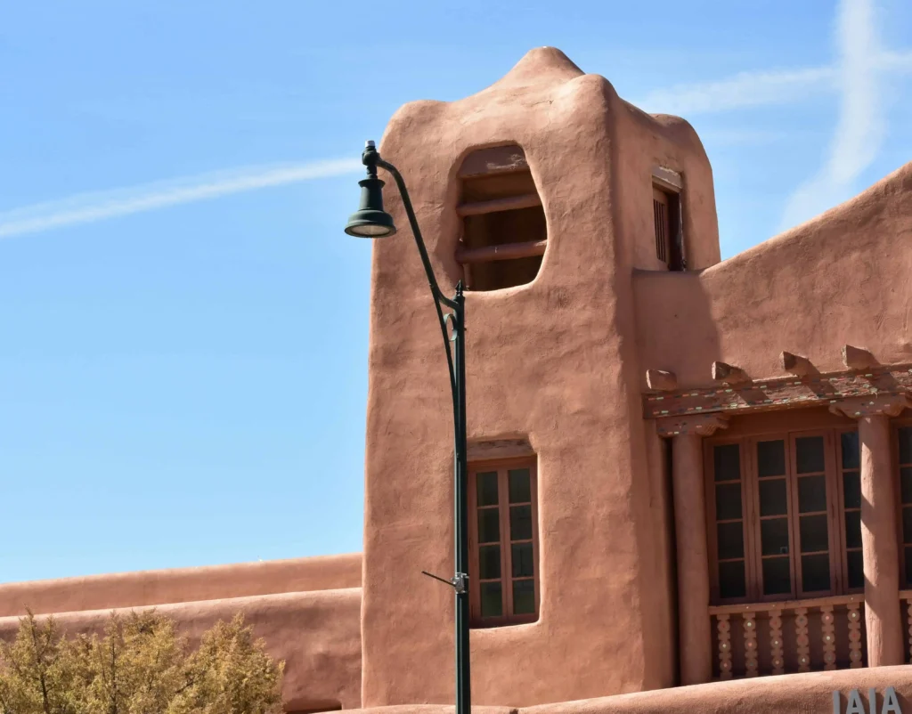 A classic adobe-style building with turquoise windows and a traditional design, embodying the signature Southwestern architectural style of Santa Fe.