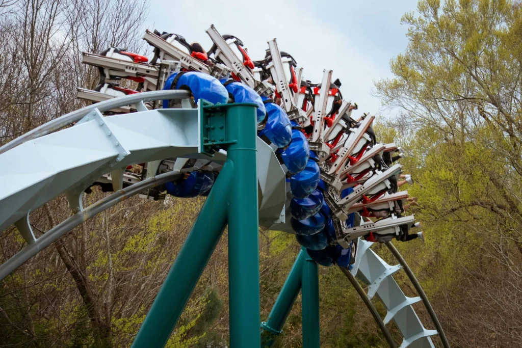 Close-up view of a thrilling roller coaster loop at Silver Dollar City, featuring vibrant blue and red seats with riders experiencing the excitement amidst lush green trees