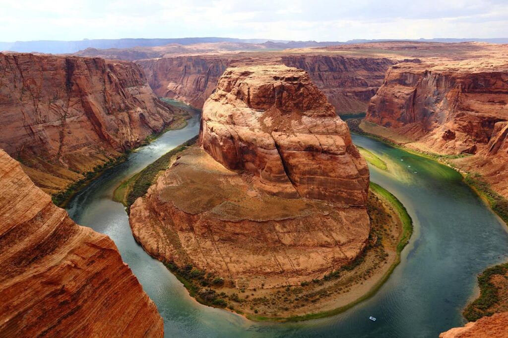 A breathtaking view of Horseshoe Bend in Grand Canyon National Park, with the Colorado River curving around the massive red rock formation under a bright, clear sky.