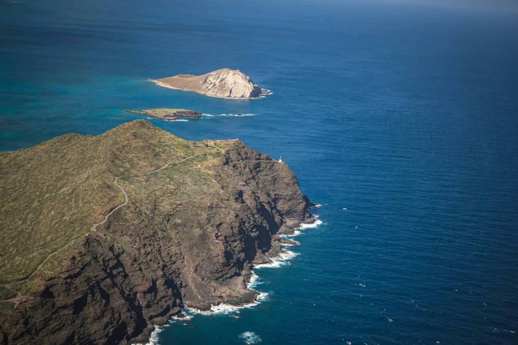 Best places to travel in the US in January: A stunning aerial view of Hawaii's rugged coastline and azure ocean, showcasing dramatic cliffs and serene offshore islets under a clear blue sky.
