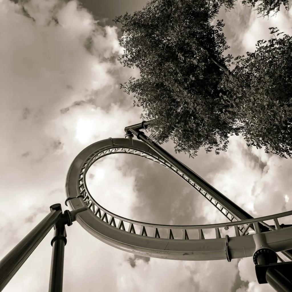 A thrilling roller coaster with a high vertical loop under a cloudy sky, showcasing the excitement of amusement park rides.