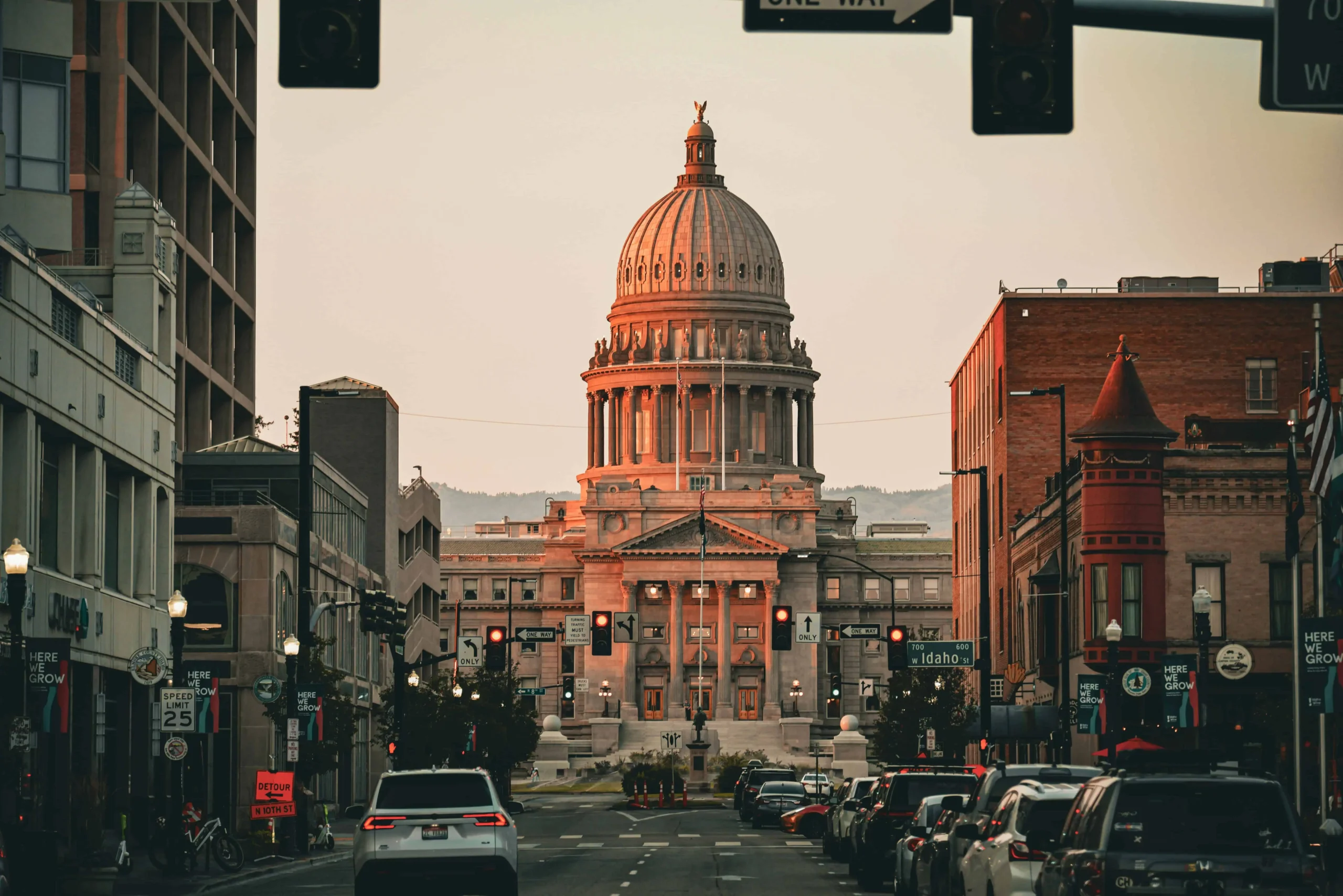 Downtown Boise, Idaho, showcasing the iconic Idaho State Capitol illuminated by warm sunset hues, with surrounding urban architecture and bustling city streets.