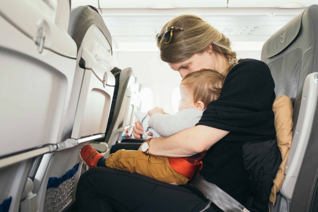 A mother holding her infant on an airplane in 2025, illustrating the best tips for traveling with an infant.