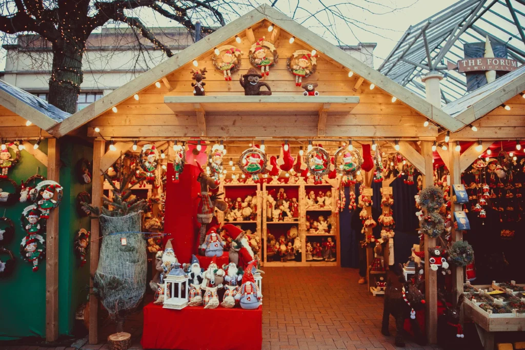 A cozy wooden stall at a European Christmas market, decorated with fairy lights and selling handmade wreaths, ornaments, and festive crafts.