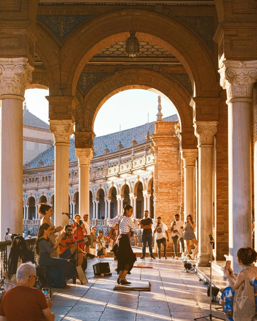 A lively flamenco performance taking place under the grand arches of Plaza de España in Seville, with spectators enjoying the show.