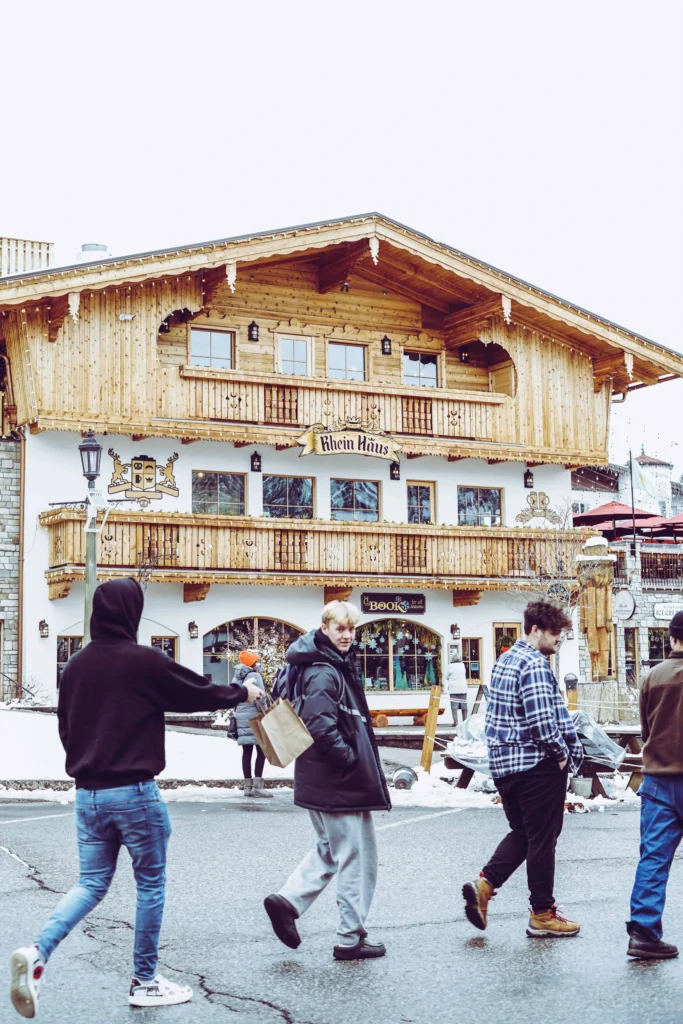 A charming Bavarian-style building in Leavenworth, Washington, adorned with wooden balconies and festive decor, with people walking on the snowy street in front