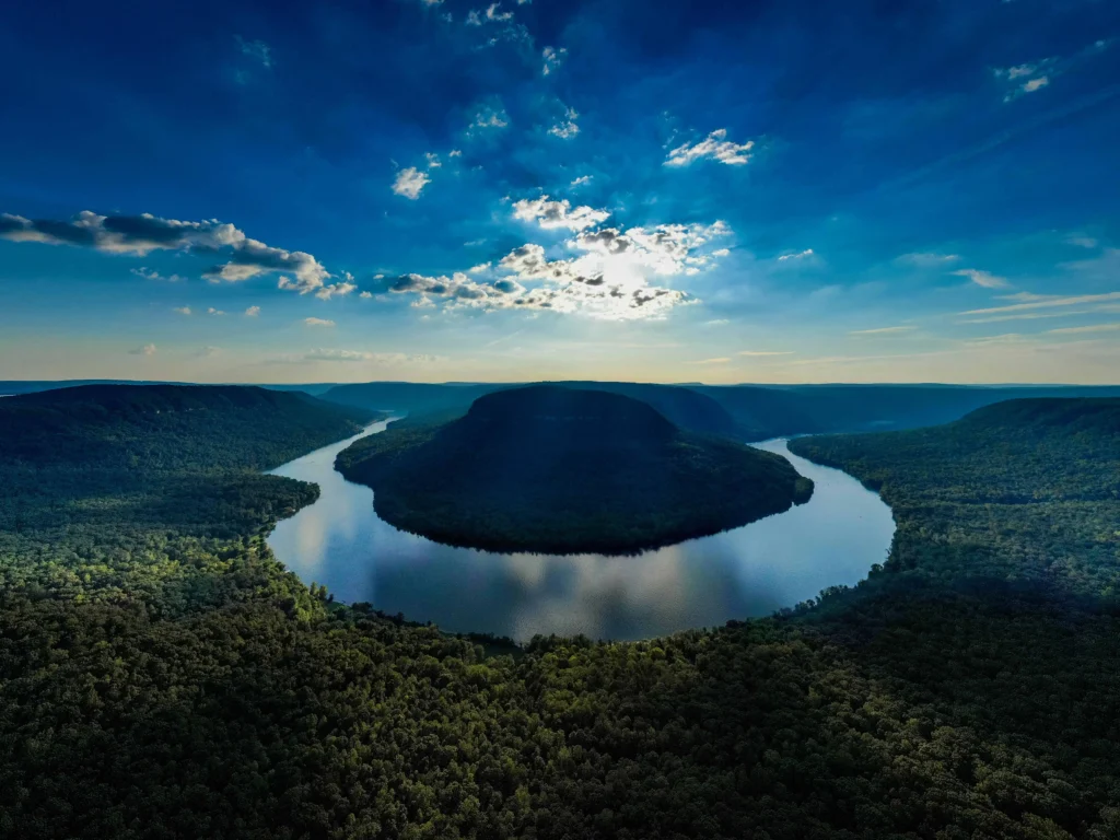 Things to do in Chattanooga: A stunning aerial view of the Tennessee River winding through the lush, green landscapes and surrounding mountains near Chattanooga, Tennessee, under a vibrant blue sky.