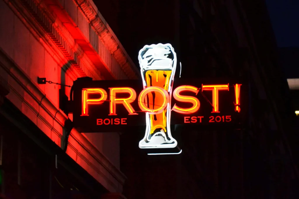 A vibrant neon sign for Prost, a popular bar in Boise, Idaho, glowing against a dark night sky