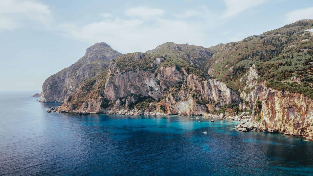 Paleokastritsa Beach in Corfu with clear blue waters and green hills, an ideal honeymoon spot for relaxation and adventure