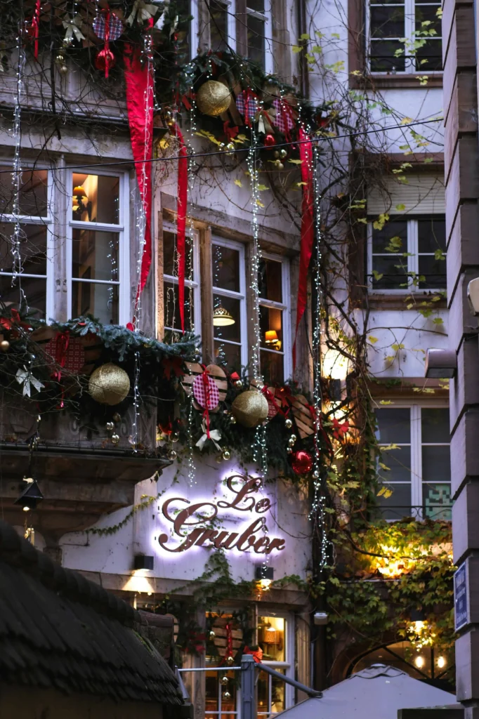 A traditional European building adorned with Christmas garlands, red ribbons, and golden ornaments, showcasing the holiday spirit.