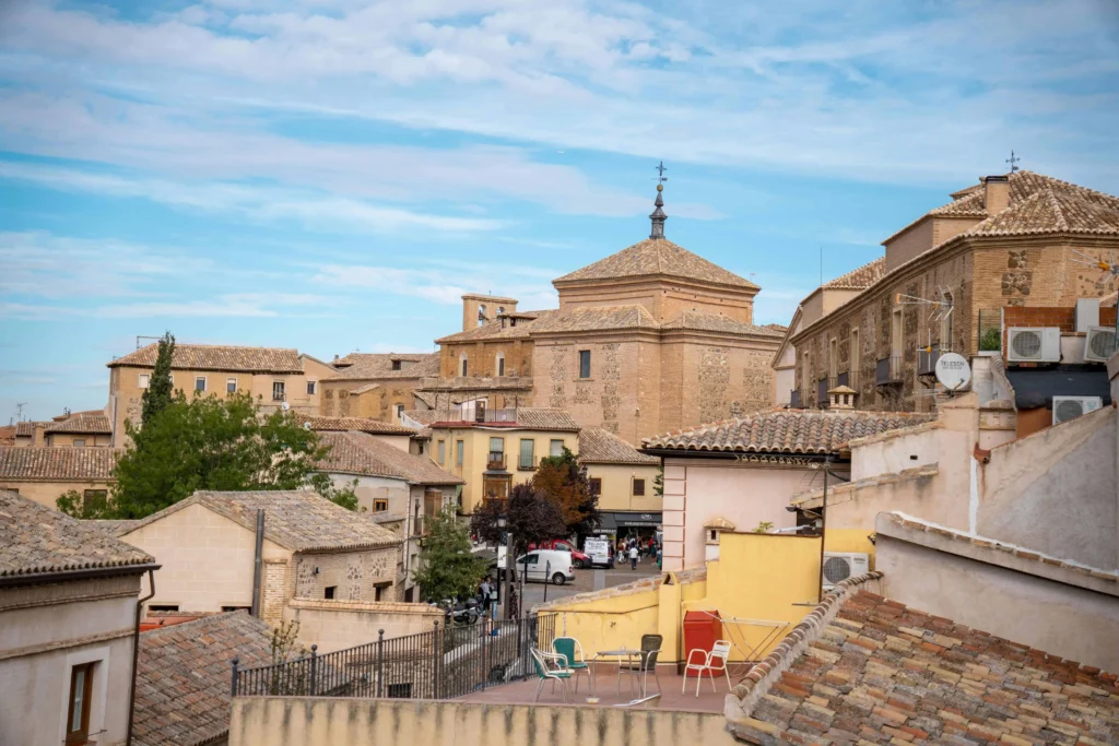 A charming view of Toledo's historic rooftops and medieval architecture, featuring stone buildings and a tranquil blue sky.