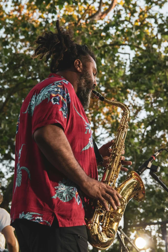 Close-up view of a jazz musician's hands playing a shiny saxophone, showcasing the intricate details of the instrument and a classic wristwatch on the artist's wrist.