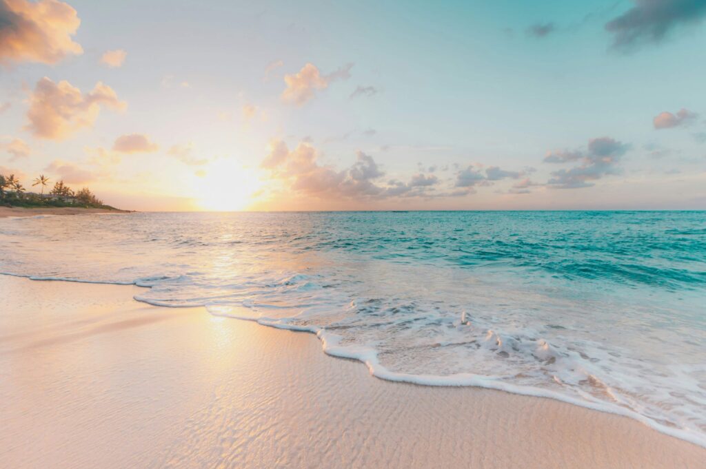 Serene Hawaiian beach at sunrise with golden light reflecting off the gentle waves, illustrating one of the 12 best times to visit Hawaii in 2025