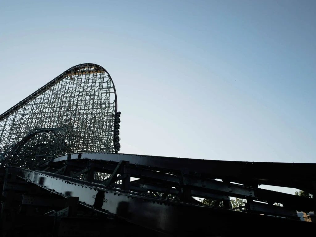 A towering wooden roller coaster at sunset, capturing the thrilling loops and steep drops that make it a highlight of amusement parks in the US