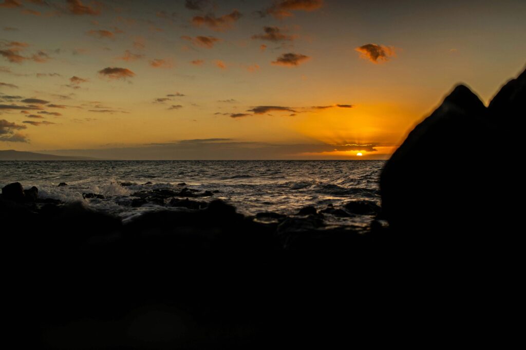 A wide-angle shot of Dragon's Teeth Maui, showcasing the jagged rock formations against the deep blue Pacific Ocean with waves crashing dramatically.