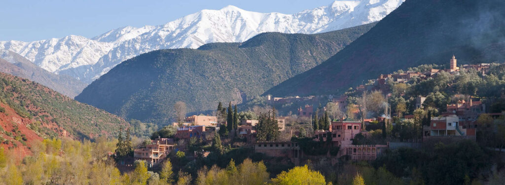 Scenic Asni Valley with lush greenery and a quaint Berber village set against the backdrop of the majestic Atlas Mountains