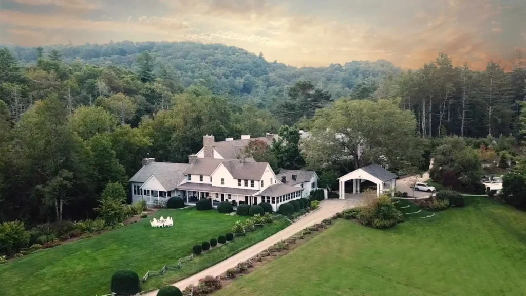 Aerial view of Half-Mile Farm in Highlands, NC, surrounded by lush greenery and rolling hills under a serene evening sky.