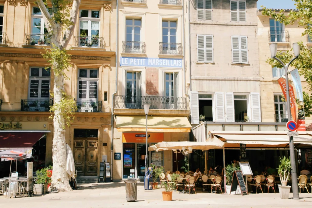 A quaint café-lined street in Aix-en-Provence with classic French architecture and outdoor seating.