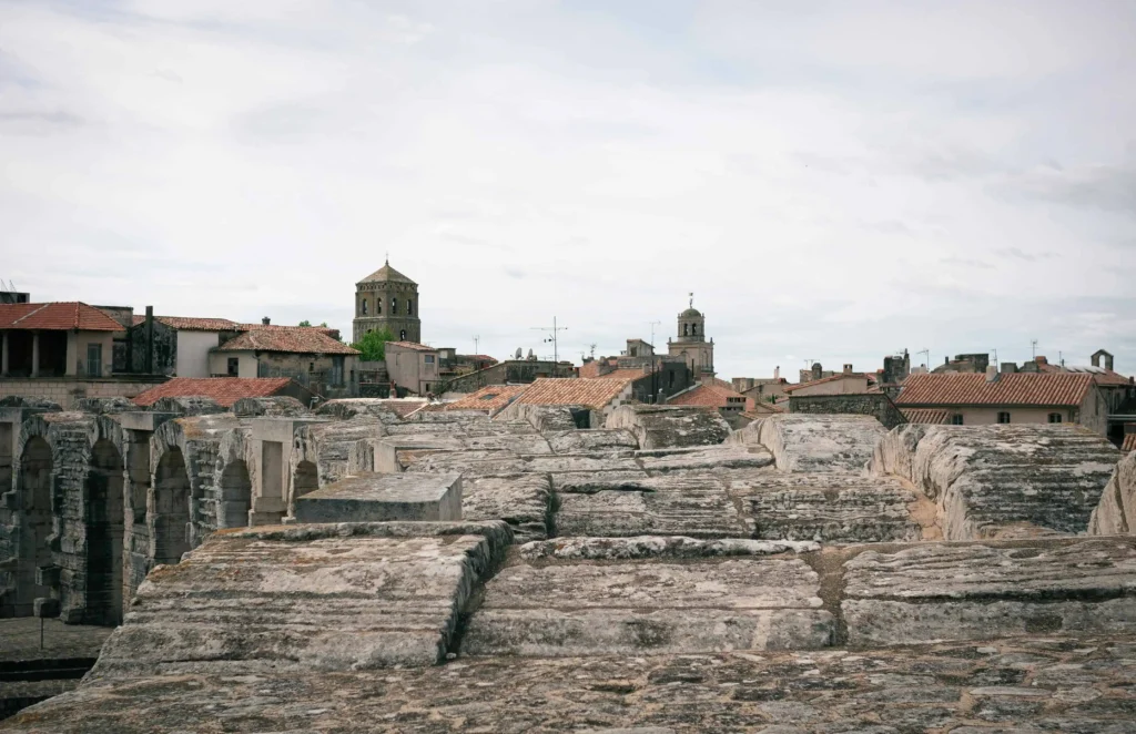 Ancient rooftops and Roman architectural remains in Arles south of France under a cloudy sky