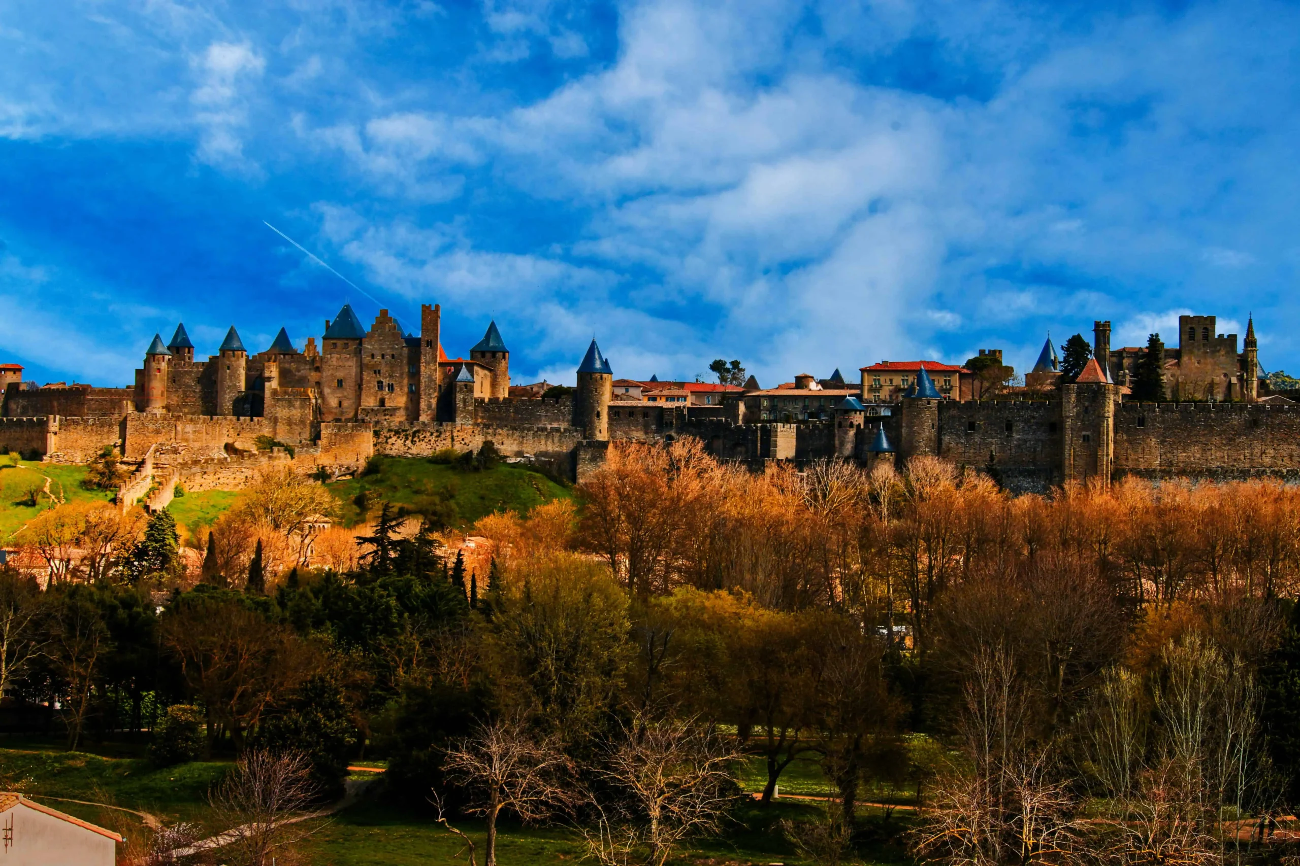 A breathtaking view of the historic medieval citadel of Carcassonne, South of France, with its iconic castle towers and fortified walls under a vibrant blue sky.