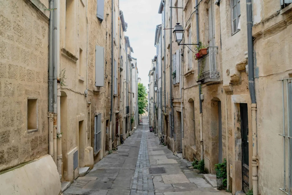 A narrow cobblestone alleyway in Montpellier lined with weathered buildings, showcasing historical charm in France