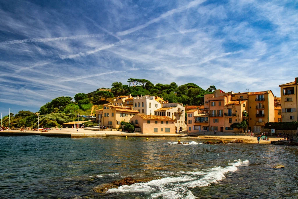 A lively harbor area with yachts docked near pastel-colored houses under a bright sky in Saint-Tropez South of France
