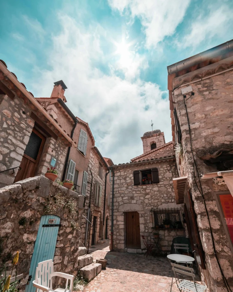 A quaint stone village with narrow streets, rustic shutters, and charming Mediterranean-style architecture under a bright blue sky.