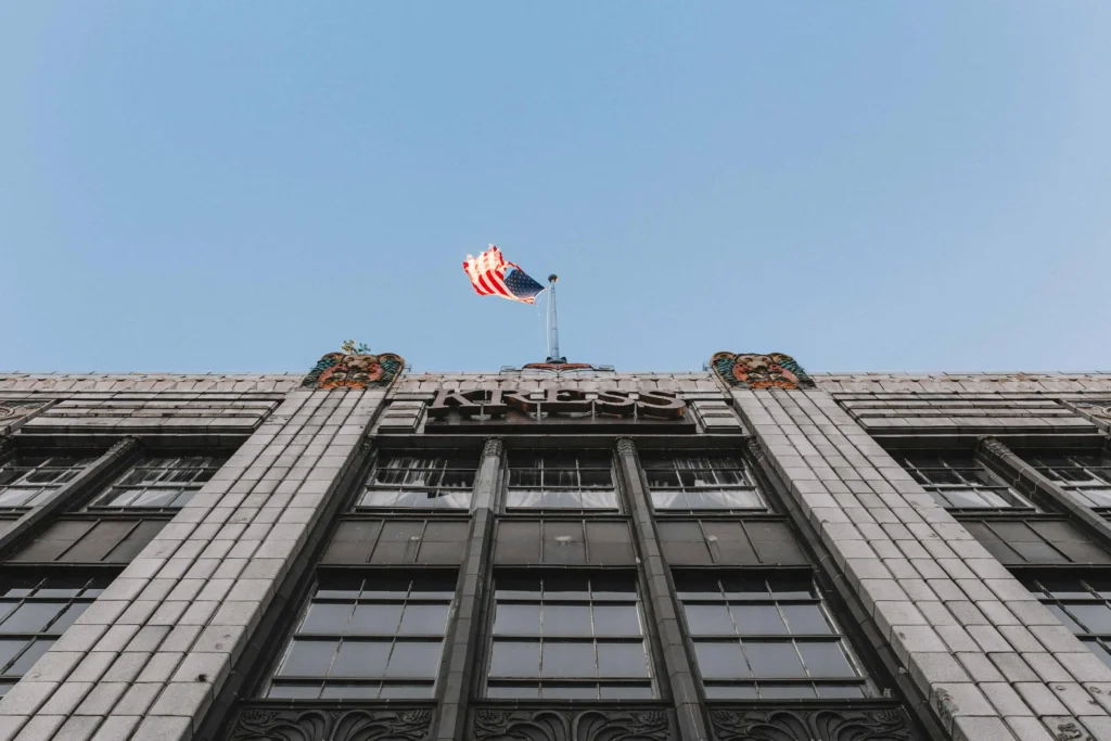 Historic building facade in Greensboro, NC, featuring intricate architectural details and an American flag waving proudly at the top, symbolizing heritage and patriotism.