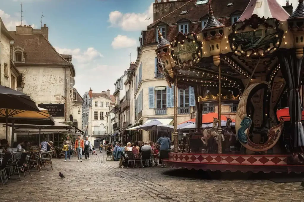 Lively cobblestone square showing activities during south of France vacation featuring a traditional carousel and outdoor cafés