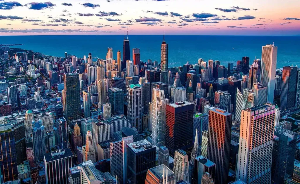 A stunning aerial view of Chicago’s downtown skyline during sunset, with skyscrapers and Lake Michigan blending into the colorful horizon.