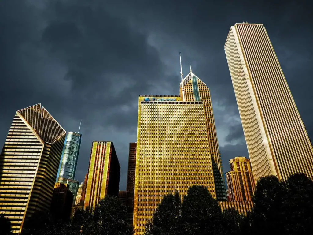 A dramatic shot of Chicago's golden skyscrapers against a dark, cloudy sky.