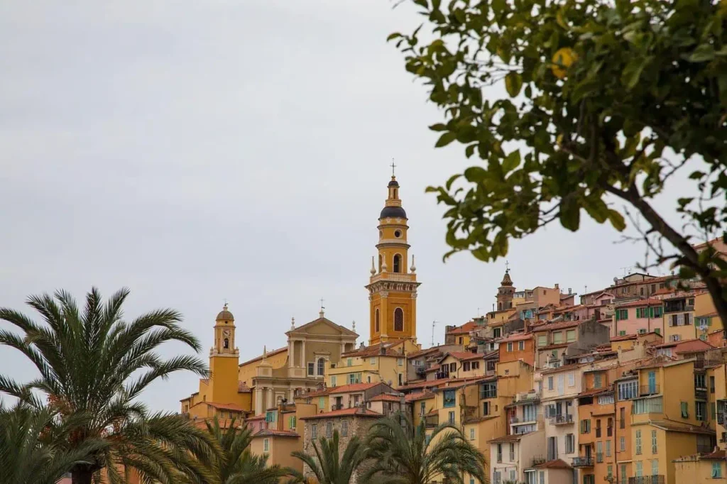 Picturesque view of colorful buildings and a historic church in hilltop town illustrating things to do in south of france vacation.