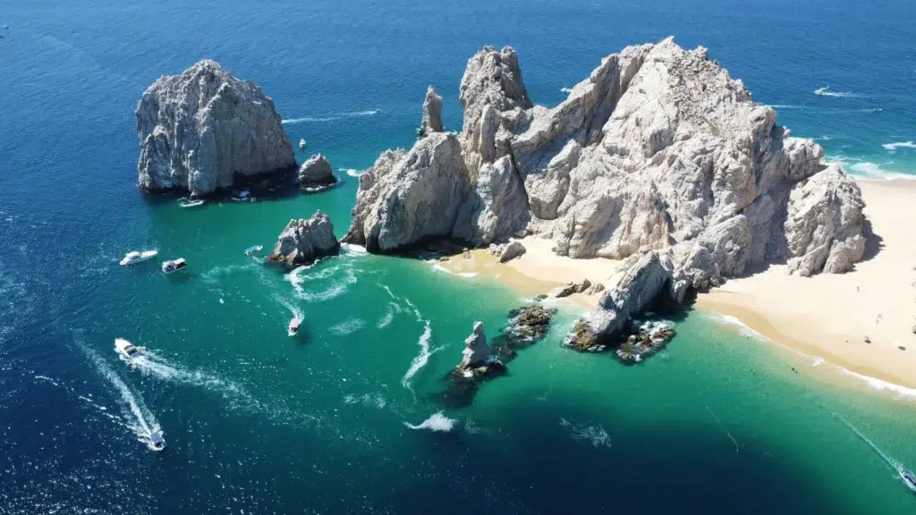 A stunning aerial view of Cabo San Lucas' famous El Arco rock formations surrounded by turquoise waters and sandy beaches.