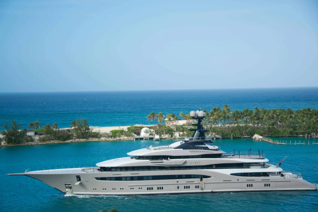 A sleek, modern luxury yacht sailing through the azure waters of the Bahamas, surrounded by lush greenery.