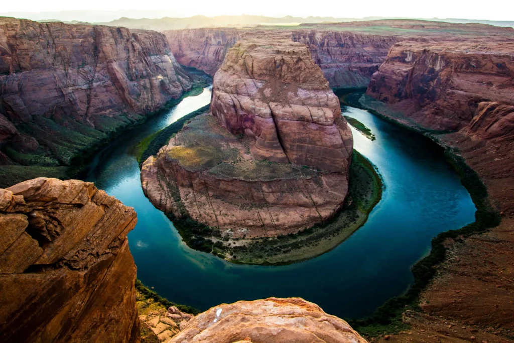 The iconic Horseshoe Bend in the Grand Canyon, with the Colorado River carving its way through towering red cliffs during golden hour.