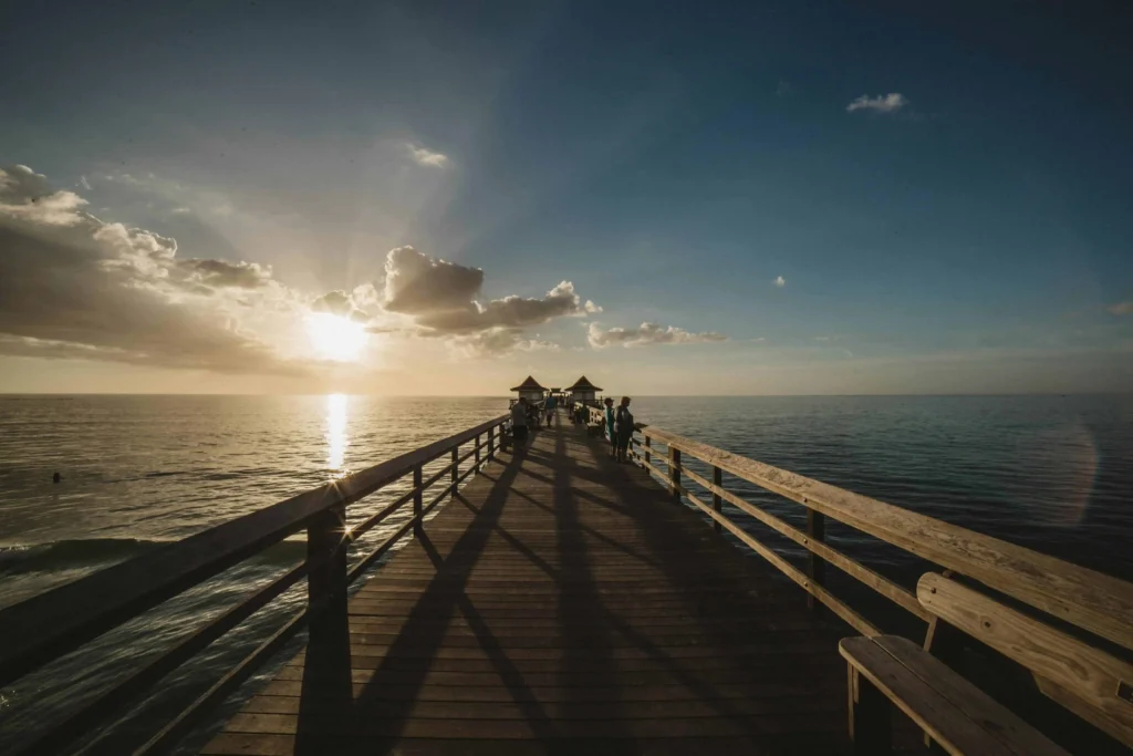 A picturesque sunset over Naples Pier with golden light reflecting on the calm waters and the pier stretching into the horizon.