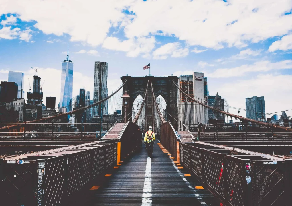 A stunning view of the Brooklyn Bridge with the Manhattan skyline in the background under a bright blue sky.