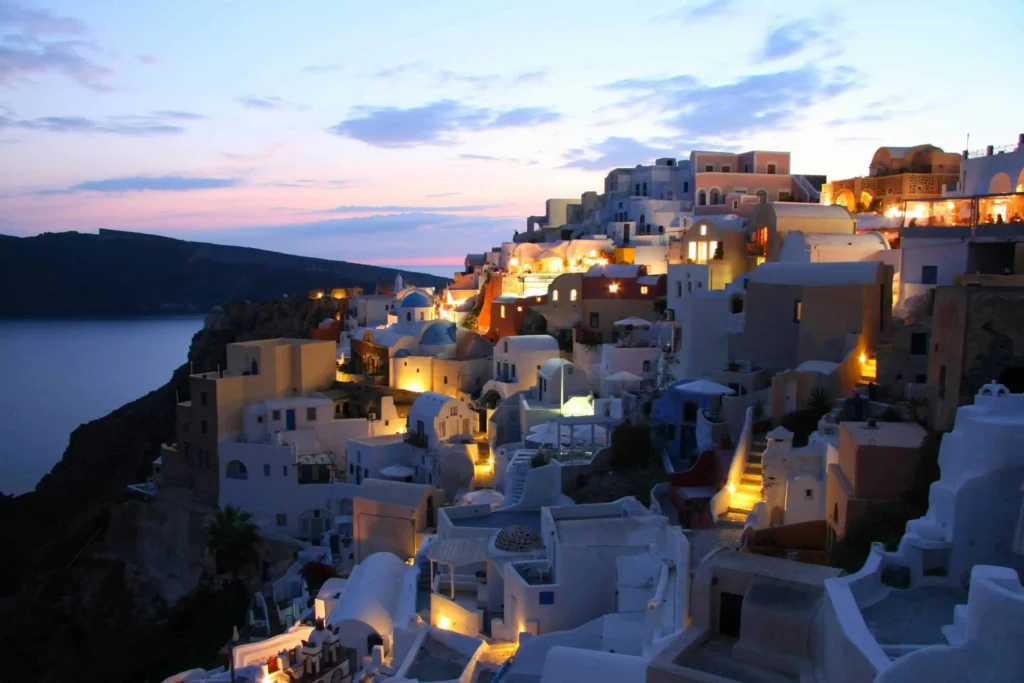 A stunning sunset view of the caldera and traditional Santorini architecture in Oia, Greece.