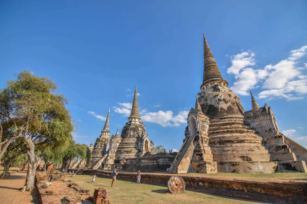 Historical ruins of Ayutthaya under a bright blue sky.