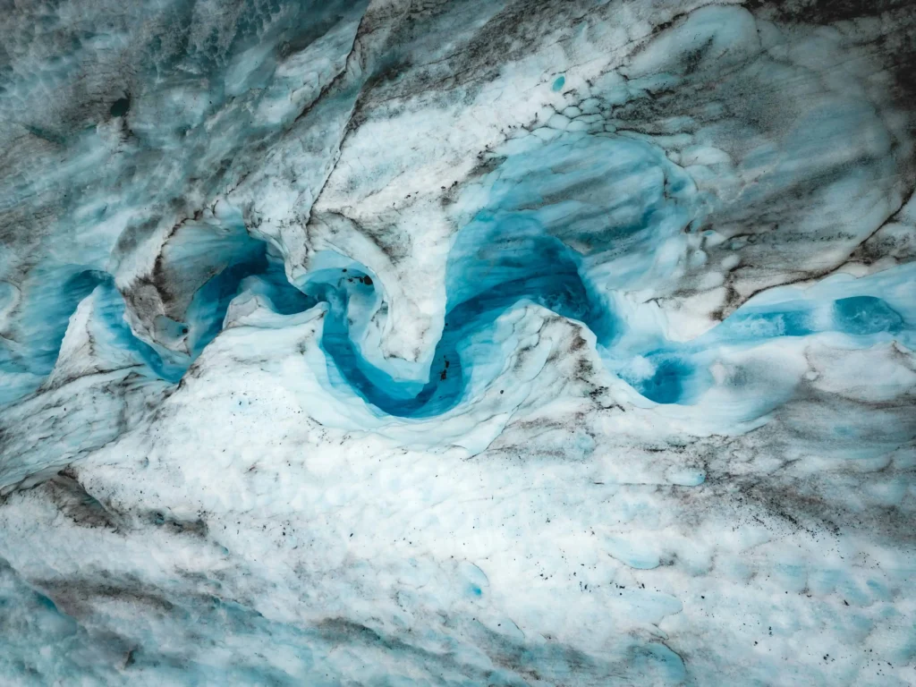 A stunning glacial ice formation featuring bright blue winding patterns, one of the natural wonders to explore.