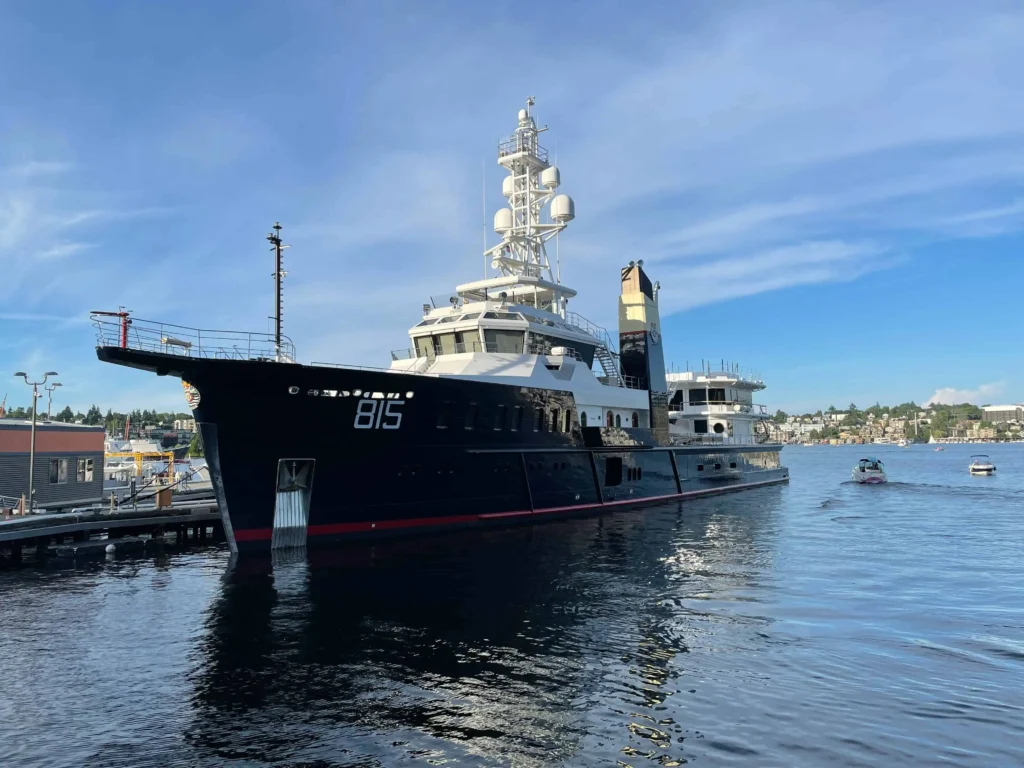 A historic ship docked at Lake Union Park under a clear blue sky, reflecting on the calm waters