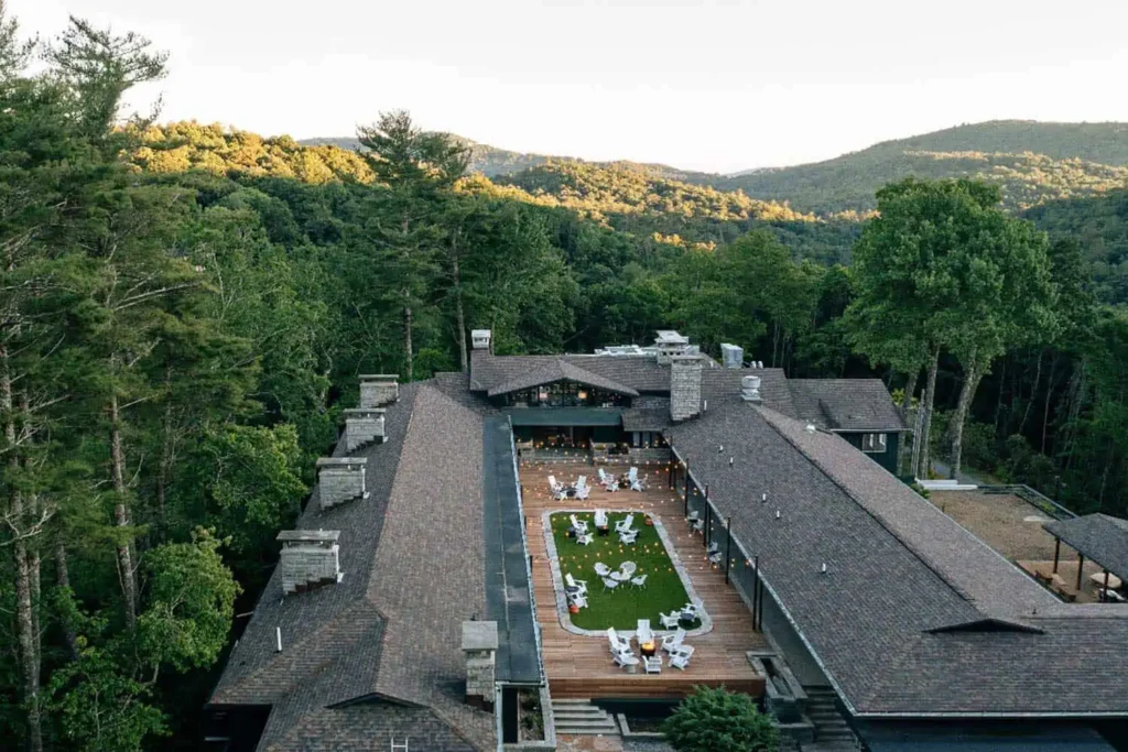 Aerial view of Skyline Lodge in Highlands, NC, showcasing its central outdoor terrace surrounded by lush forested hills.