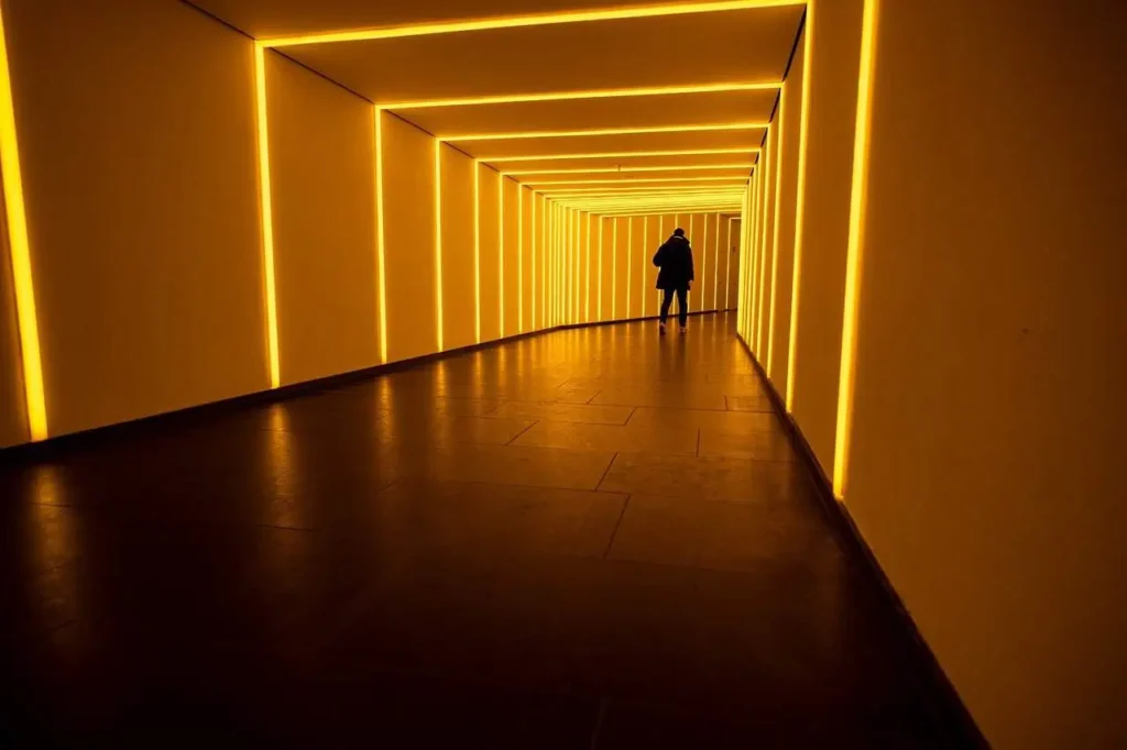 A captivating view of a modern yellow-lit tunnel, showcasing a person walking through the corridor, highlighting the unique ambiance of the Washington DC underground museum.