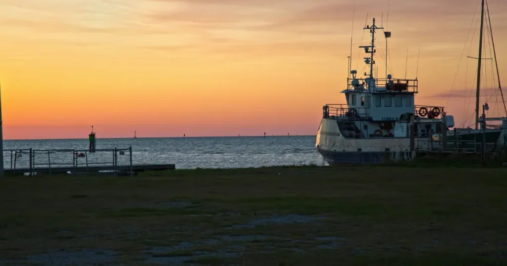 A scenic view of a fishing boat at sunset in Dauphin Island, Alabama.