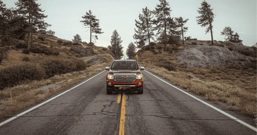 A red GMC truck driving through a scenic mountain road in Julian CA, capturing the essence of a road trip in Julian