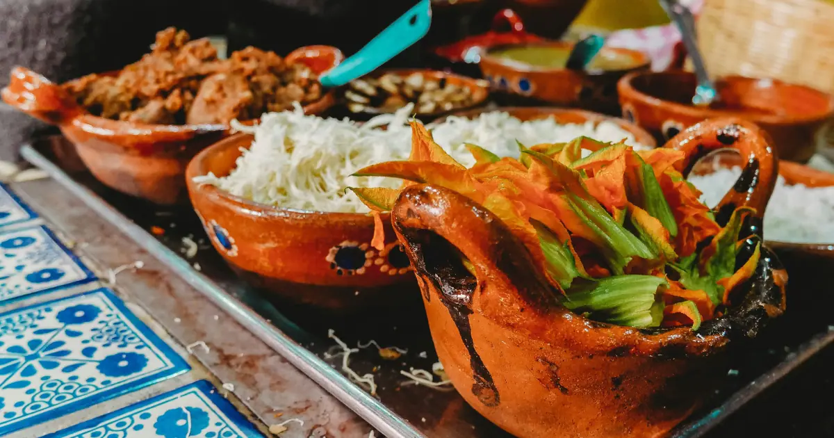 Traditional Mexican dishes served in rustic clay bowls with fresh ingredients in a vibrant setting.
