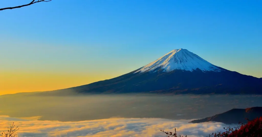 Mount Fuji with a glowing sunrise and yellowish hues in the sky