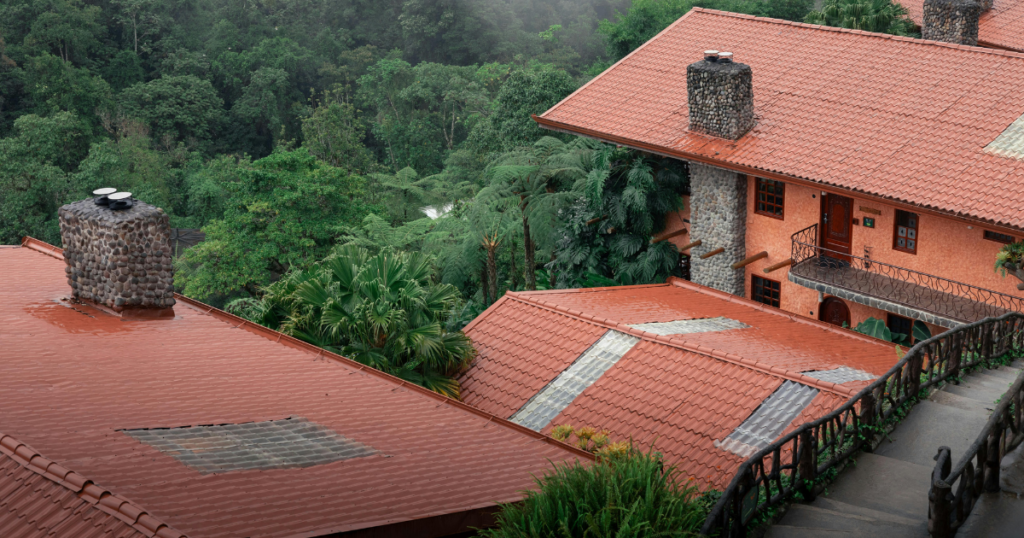 Red-roofed eco-lodge surrounded by lush green rainforest in Costa Rica, offering sustainable and serene accommodation.